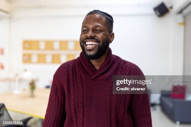 fröhlicher afrikanischer junger mann im startup-büro - portrait of man smiling black jumper stock-fotos und bilder