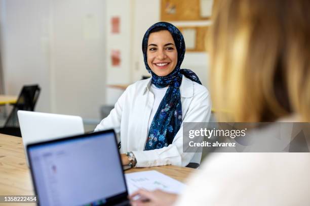 middle eastern woman discussing with a colleague at startup - eastern european woman stockfoto's en -beelden