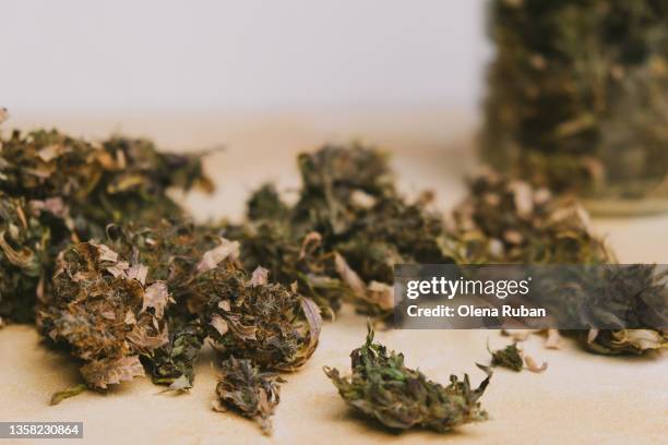 close-up of dried cannabis cones scattered from glass bottle. - cannabis droge stockfoto's en -beelden