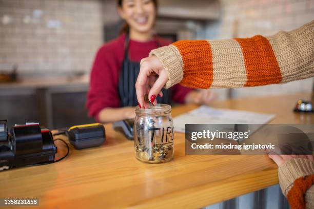 unrecognizable female customer leaving the tips at the tip jar - gratuity stock pictures, royalty-free photos & images