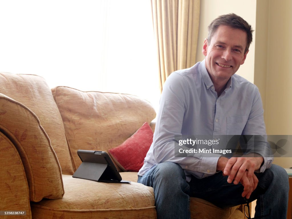 Man sitting on sofa smiling at camera.