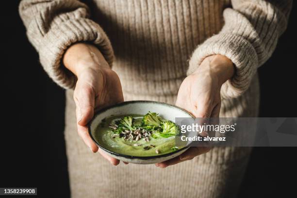 woman holding a fresh bowl of homemade broccoli soup - crucifers stock pictures, royalty-free photos & images