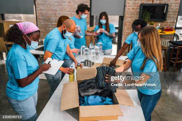 diverse volunteers team packing donation boxes - homeless shelter stock pictures, royalty-free photos & images