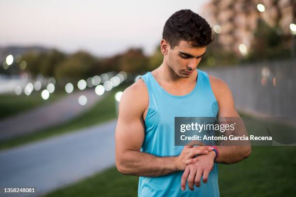 man training fitness and running in public city park, looking smart watch statistics - men wearing bras photos stock pictures, royalty-free photos & images