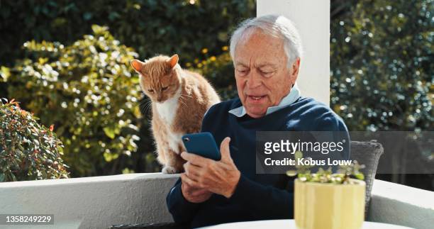 shot of a senior man sitting alone outside and using his cellphone - man reliable learning stockfoto's en -beelden