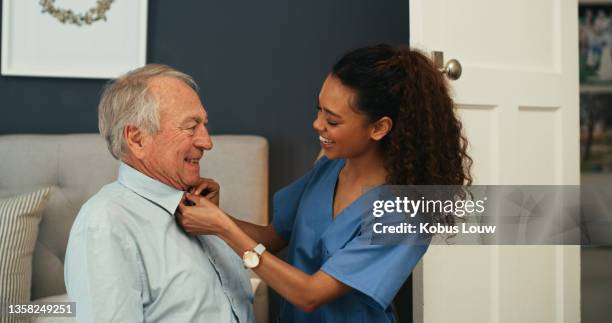 shot of an attractive young nurse helping her senior patient get dressed in the morning at home - getting dressed stock pictures, royalty-free photos & images