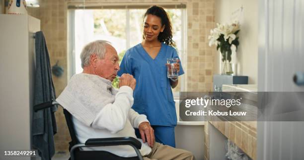 shot of an attractive young nurse helping her senior patient brush his teeth in the bathroom at home - brushing teeth stock pictures, royalty-free photos & images