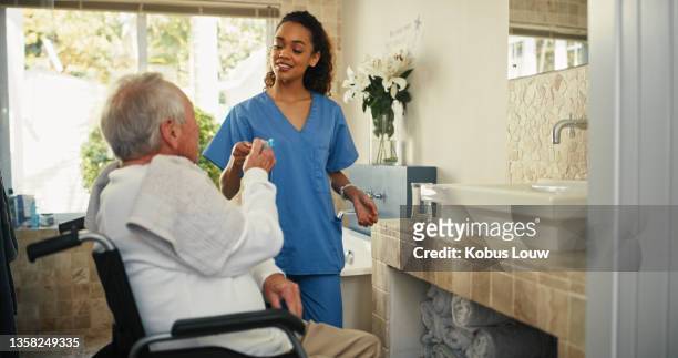 shot of an attractive young nurse helping her senior patient brush his teeth in the bathroom at home - personal care stock pictures, royalty-free photos & images
