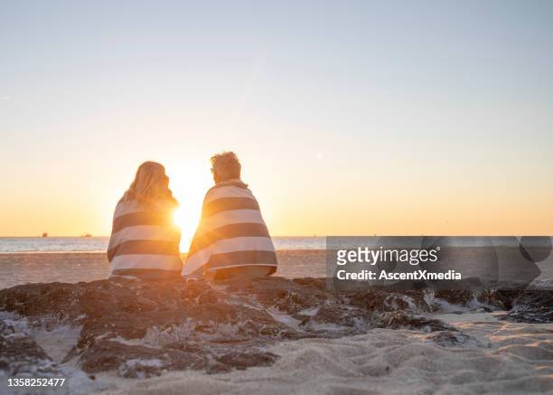 pareja madura se relaja en la playa de arena al amanecer - océano pacífico fotografías e imágenes de stock