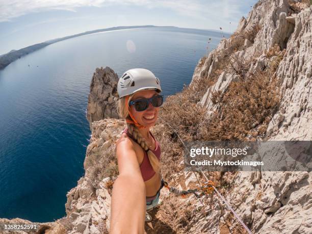 lo scalatore sulla ferrata sul mare scatta una foto selfie in vetta - extreme foto e immagini stock