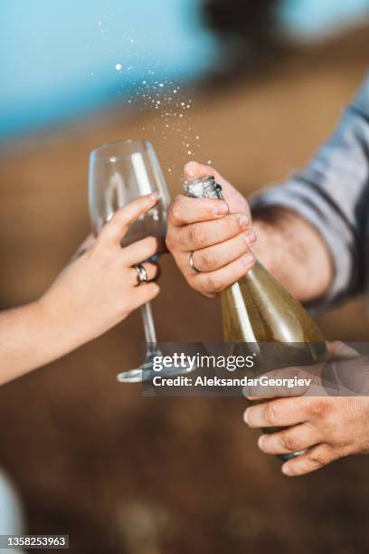 male uncorking champagne bottle for himself and wife - drunk husband stock pictures, royalty-free photos & images