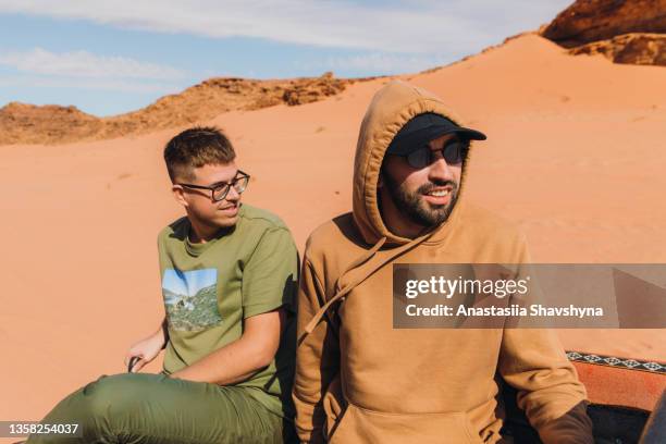 two men traveler riding thought the sands at wadi rum desert - middle east friends stock pictures, royalty-free photos & images