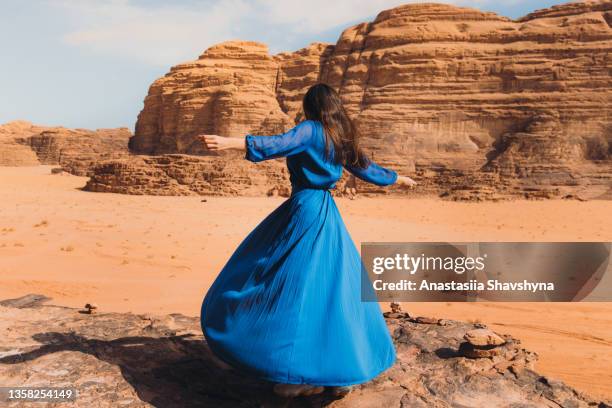 frau in blauem kleid, die die malerische landschaft der wüste wadi rum betrachtet - hot middle eastern women stock-fotos und bilder