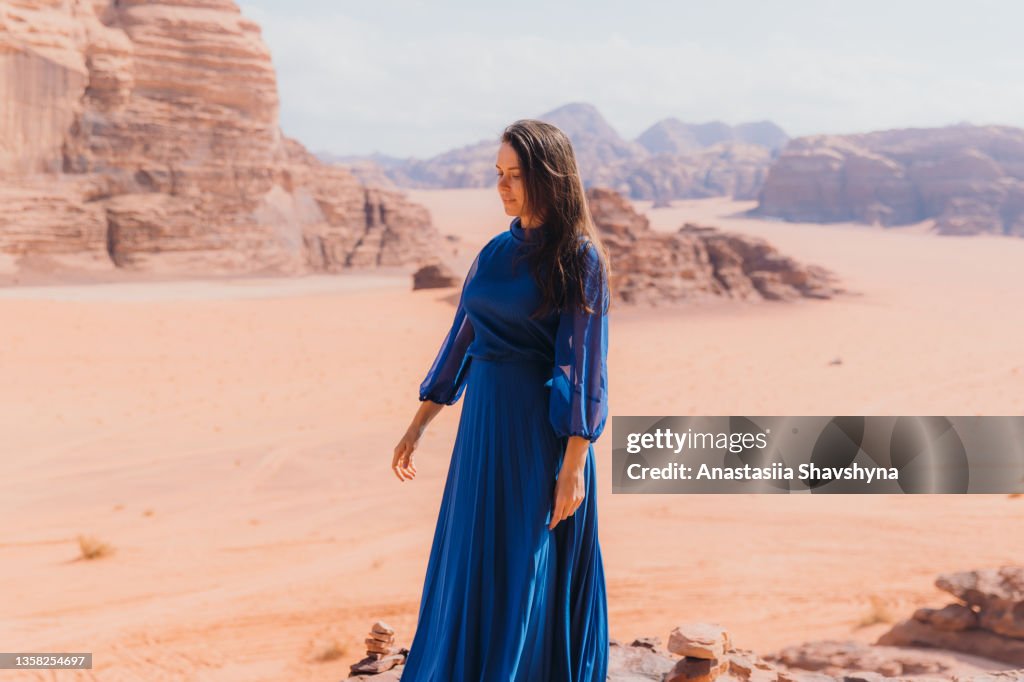 Woman in blue dress contemplating the scenic landscape of Wadi Rum desert