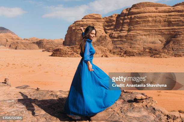 frau in blauem kleid, die die malerische landschaft der wüste wadi rum betrachtet - hot middle eastern women stock-fotos und bilder