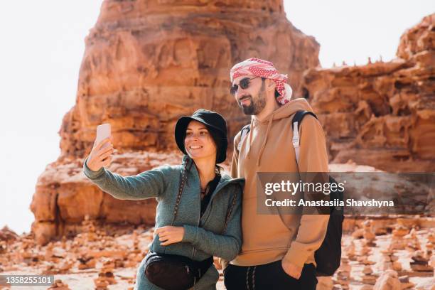 young woman and man taking selfie during sunny day in wadi rum desert - hot middle eastern women stock pictures, royalty-free photos & images