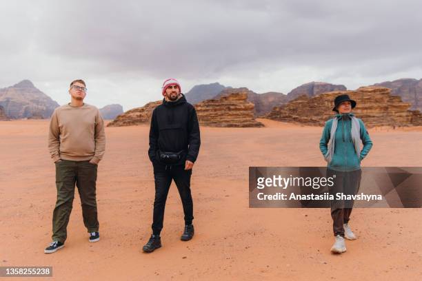 freunde reisende, die am bewölkten morgen in der wüste wadi rum spazieren gehen - hot middle eastern women stock-fotos und bilder