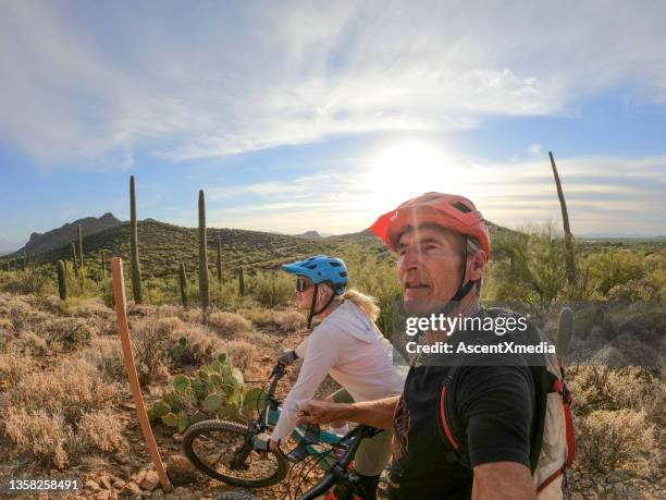 mountain biking couple follow trail, in desert - tucson arizona stock pictures, royalty-free photos & images