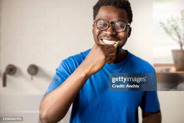 hombre cepillándose los dientes en el baño - lavarse los dientes fotografías e imágenes de stock