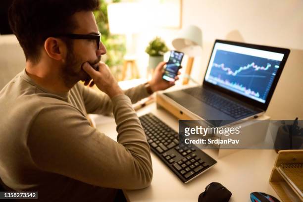 caucasian man investing or trading in bitcoin or other cryptocurrencies - traders stockfoto's en -beelden