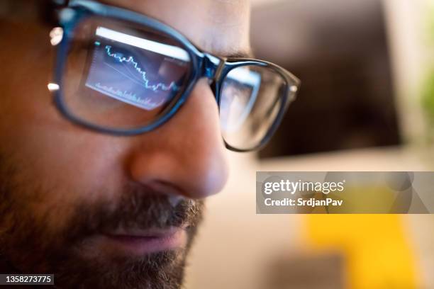 close up of crypto graph reflection into male trader eyeglasses - head shot close looking stockfoto's en -beelden