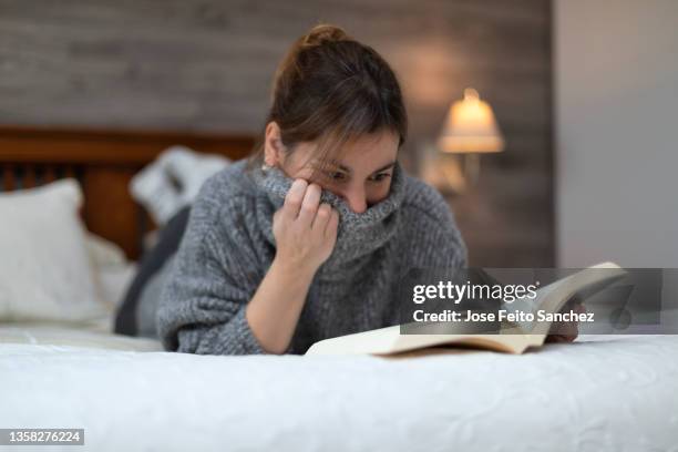 woman reading a book lying on bed - scary stock pictures, royalty-free photos & images