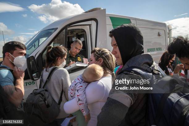 An immigrant family from Cuba waits to be transported to a U.S. Border Patrol processing center on December 09, 2021 in Yuma, Arizona. Women and...