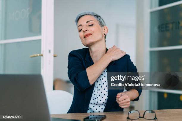 young businesswoman rubbing her neck while working in the office. - neck stretch stock pictures, royalty-free photos & images