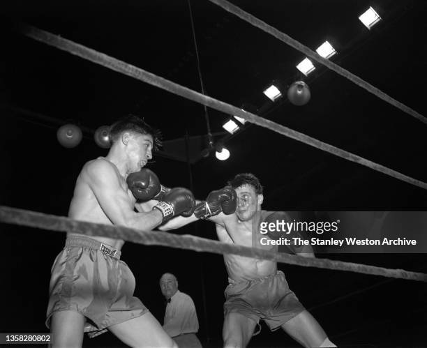Al Andrews from Wisconsin, seems to be resting dreamily on the glove of Gustav Scholz of Berlin, Germany, who also takes a punch in this exchange of...