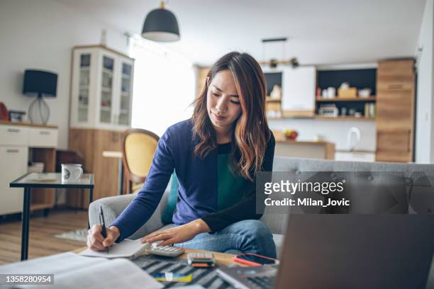 young japanese woman doing her finances at home - orca imagens e fotografias de stock