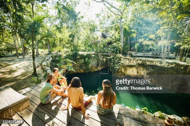 wide shot of group of friends relaxing on platform above cenote at eco resort in jungle - day 4 stock-fotos und bilder