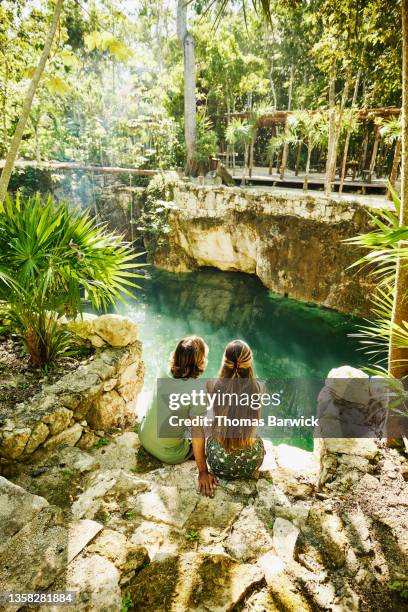 wide shot rear view of couple relaxing at edge of cenote at eco resort in jungle - in touch with nature stock pictures, royalty-free photos & images