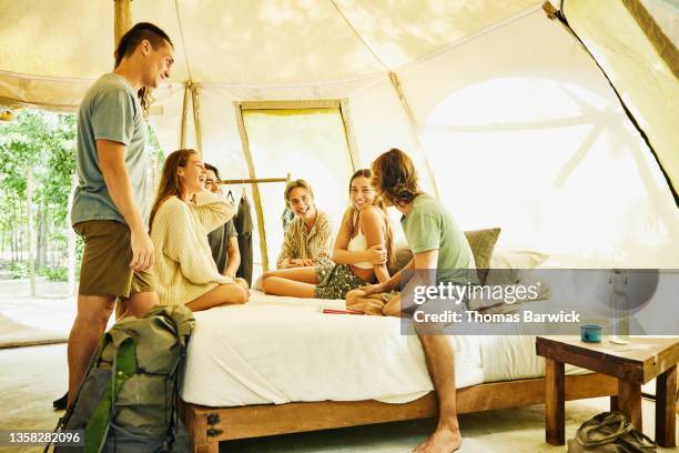 wide shot of smiling and laughing group of friends hanging out in tent at eco resort in jungle - luxury tent stock pictures, royalty-free photos & images