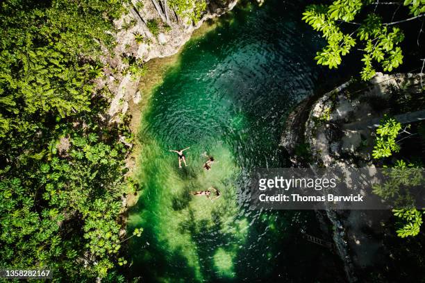 extreme wide shot aerial view of friends relaxing in cenote at eco resort in jungle - wereldreis stockfoto's en -beelden
