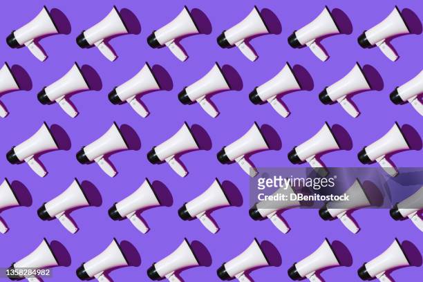 white megaphones pattern with black ornament on purple background. shout, message, announcement and news concept. - horn press stock pictures, royalty-free photos & images