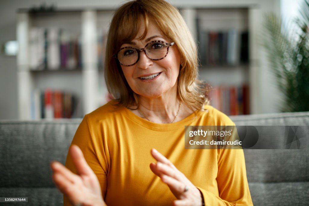 Lächelnde reife Frau, die zu Hause per Videoanruf spricht