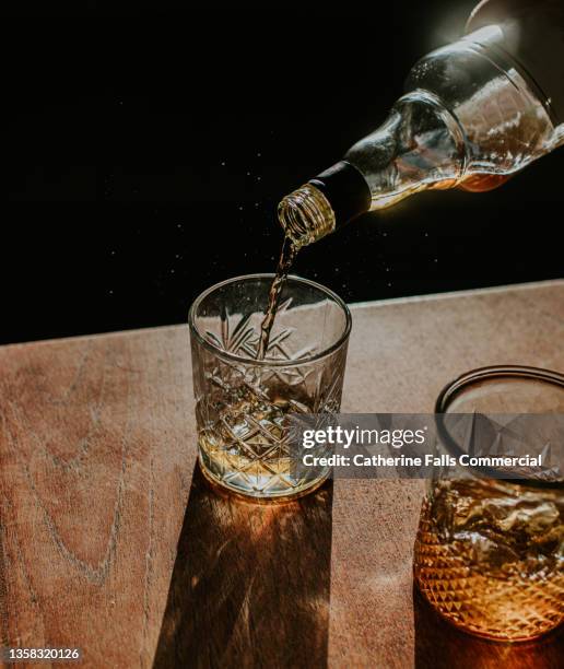 whisky pour from a bottle into a cut glass tumbler - whisky bar stock-fotos und bilder