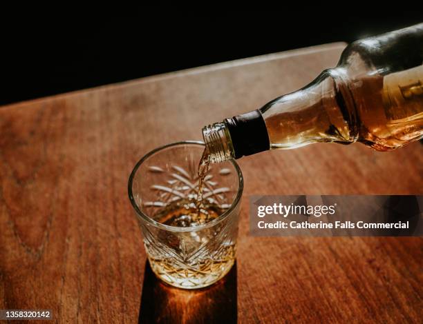 whisky pour from a bottle into a cut glass tumbler - dram stock-fotos und bilder