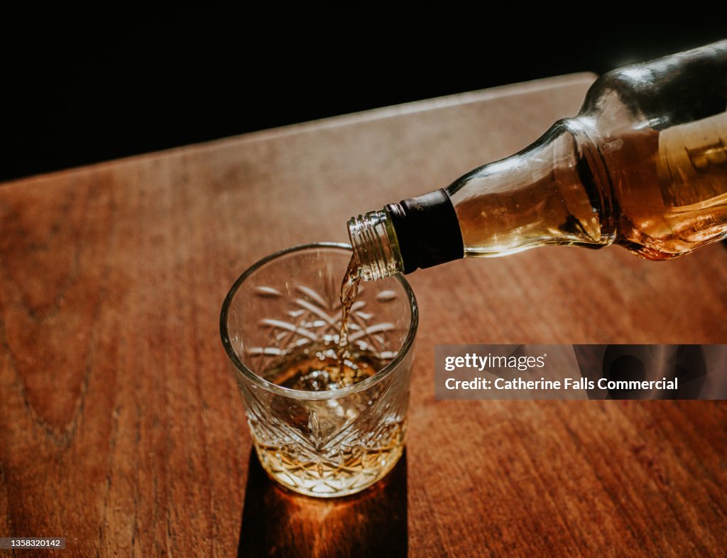 Whisky Pour from a bottle into a cut glass tumbler