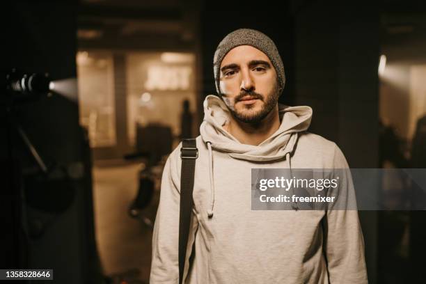 portrait of young man in hooded shirt while standing in gym locker room - man backstage stock pictures, royalty-free photos & images