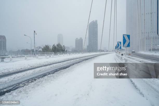 empty city street on a snowy day - snow covered road stock-fotos und bilder