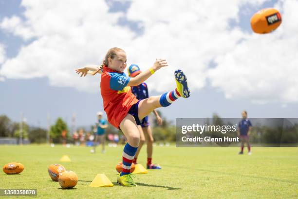 Girl kicks the ball at a combined AFL Queensland / Gold Coast Suns football clinic at Metricon Stadium on December 11, 2021 in Gold Coast, Australia.