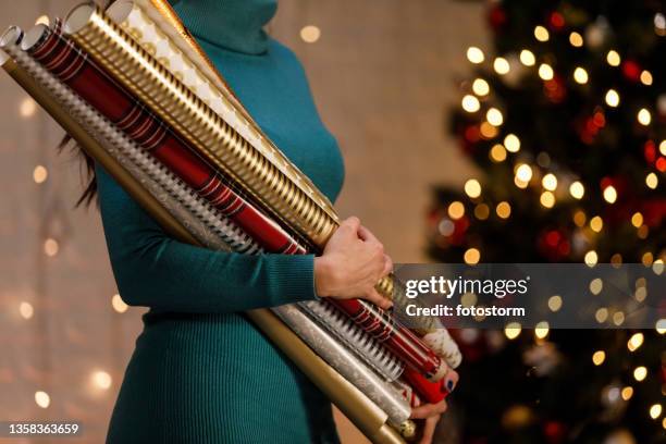 copy space shot of woman holding rolls of beautiful christmas wrapping papers - roll of wrapping paper stock pictures, royalty-free photos & images