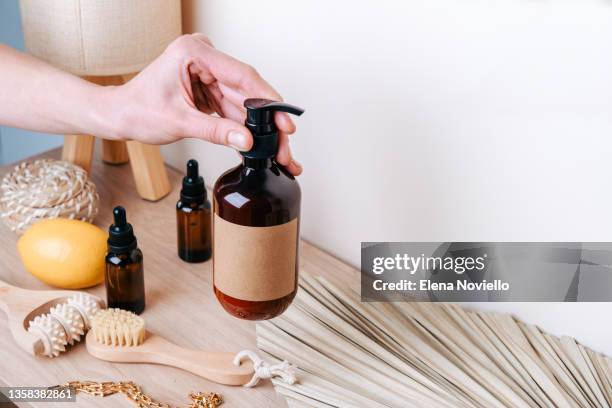 a woman's hand holds a bottle of moisturizing lotion, a daily beauty routine. home care products for the skin of the face, body and hair. moisturizing and cleansing the skin, massage brushes. - seife stock-fotos und bilder