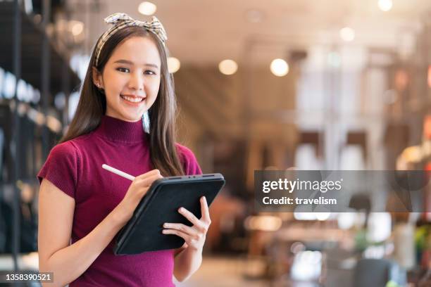 smart confidence asian female startup entrepreneur small business owner businesswoman wear smart casual cloth smile hand use tablet woking inventory checking in showroom office daytime background - filmteam stockfoto's en -beelden