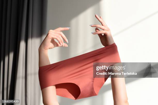 seamless female panties in the hands of the girl. - cropped trousers stock-fotos und bilder