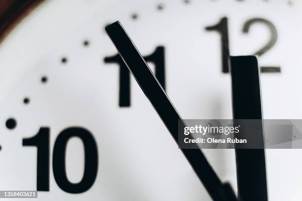 round wall clock showing 11:55. - clock photos et images de collection