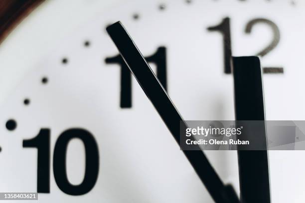 round wall clock showing 11:55. - corrida contra o tempo - fotografias e filmes do acervo