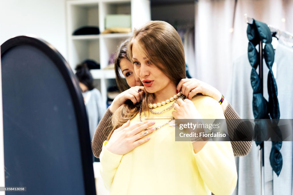 Two middle-aged women pick up clothes in a boutique