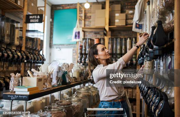 shot of a young woman filling a jar with product while shopping - duurzaam consumeren stockfoto's en -beelden